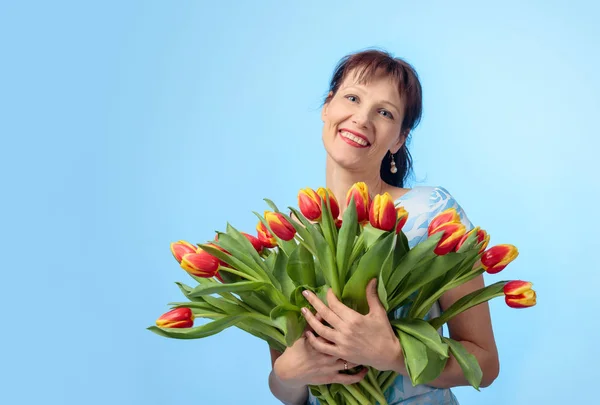 Attractive woman in blue dress with a bouquet of red and yellow — Stock Photo, Image