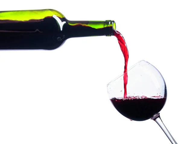 Rode wijn uit fles aan geïsoleerd op wit glas gieten. — Stockfoto