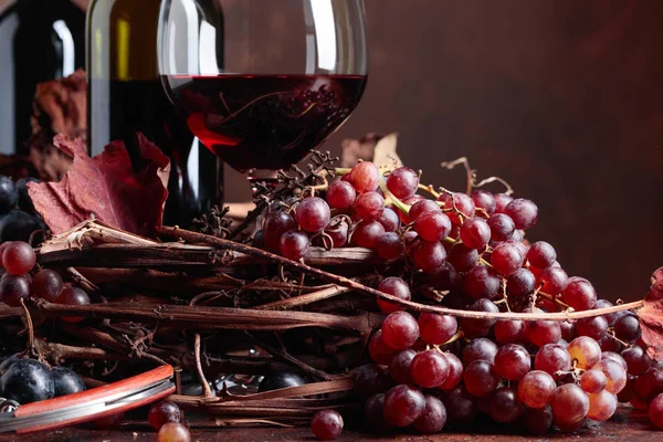 Red wine and  grapes with dried up vine leaves. — Stock Photo, Image