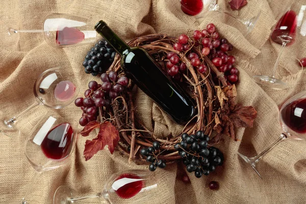 Vinho tinto e uvas em uma mesa coberta com serapilheira . — Fotografia de Stock