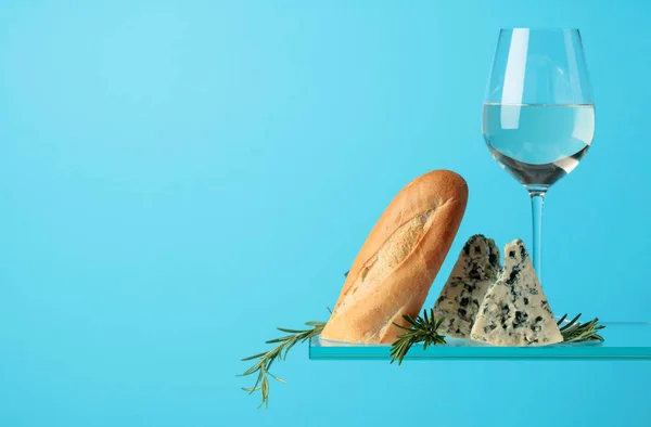Blue cheese with bread, white wine and rosemary on a blue backgr