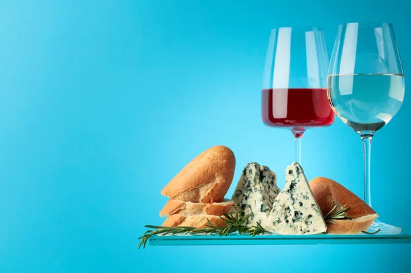 Blue cheese with bread, wine and rosemary on a blue background. — Stock Photo, Image
