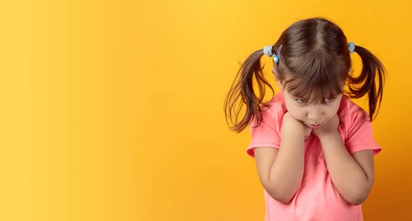 Offended girl in a pink t-shirt on an orange background. — Stock Photo, Image