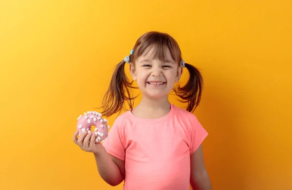 Four-year-old girl in a pink t-shirt eat donut. — Stock Photo, Image