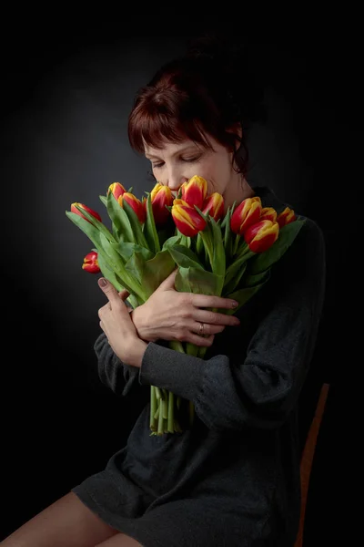 Mulher atraente com um buquê de tulipas vermelhas e amarelas . — Fotografia de Stock
