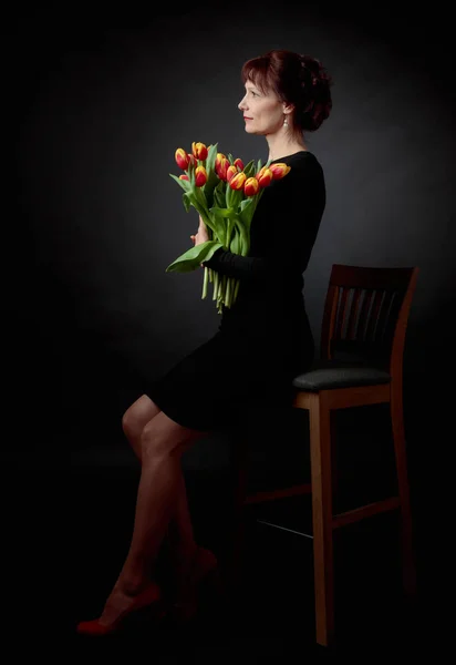 Attraktive Frau mit einem Strauß roter und gelber Tulpen. — Stockfoto