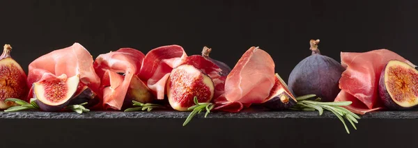 Prosciutto com figos e alecrim sobre fundo escuro . — Fotografia de Stock