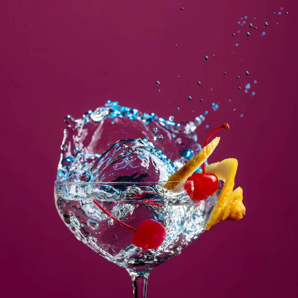 Cocktail in glass with splashes garnished with lemon and cherrie — Stock Photo, Image