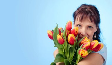 Bir buket kırmızı ve sarı mavi elbiseli çekici kadın 