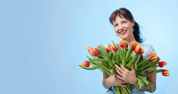Attractive woman in blue dress with a bouquet of red and yellow — Stock Photo, Image