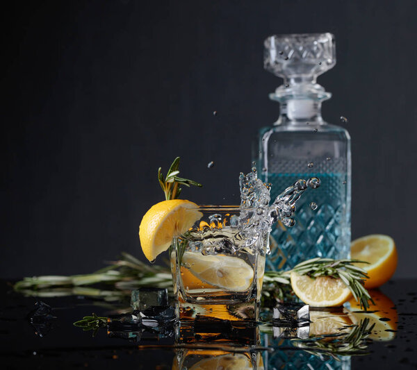 Cocktail gin-tonic with lemon slices and twigs of rosemary.