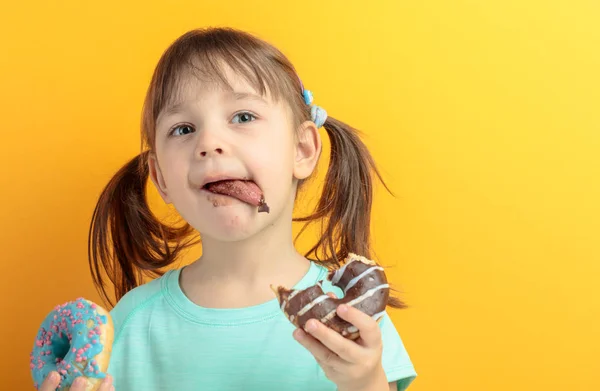 Девушка в бирюзовой рубашке ест пончики . — стоковое фото