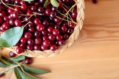 Kiraz ahşap arka plan üzerinde sepet içinde yapraklarla. 