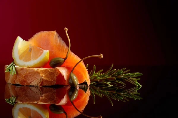 Sanduíche com filetes de truta, fatia de limão, alcaparras e alecrim . — Fotografia de Stock