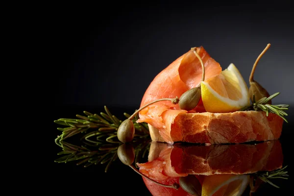 Smörgås med öring filéer, citron skiva, kapris och rosmarin. — Stockfoto
