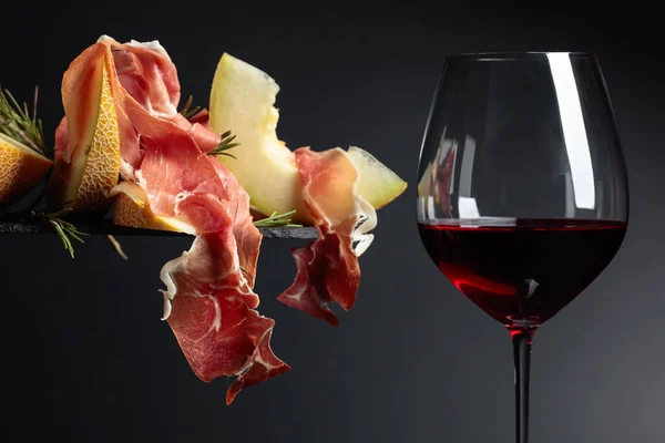 Red wine with prosciutto and melon. — Stock Photo, Image