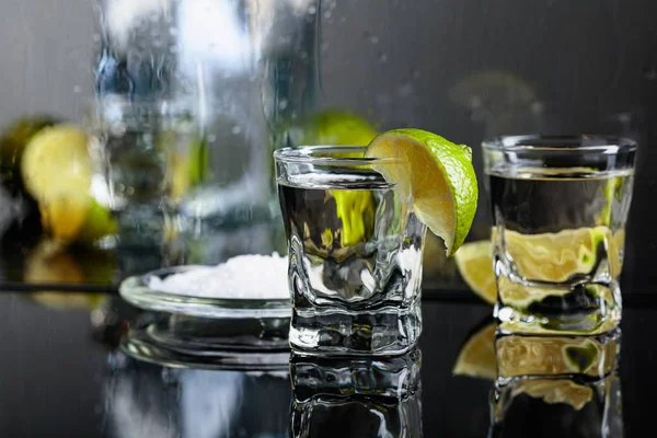 Bicchieri di tequila con lime e sale sul nero riflettente ba — Foto Stock