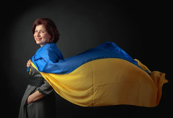 Happy middle-aged woman in a gray dress with a blue and yellow s — Stock Photo, Image