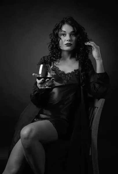 Retrato de morena atraente com copo de conhaque em um preto — Fotografia de Stock