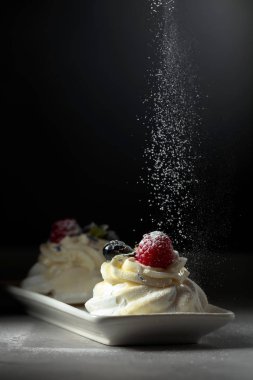 Tatlı Pavlova ile pudra şekeri serpilir.