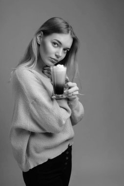 Güzel sarışın bir kupa kahve kremalı tutan bir kazak