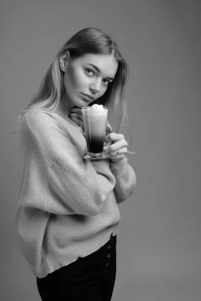 Bella bionda in un maglione con una tazza di caffè con crema — Foto Stock