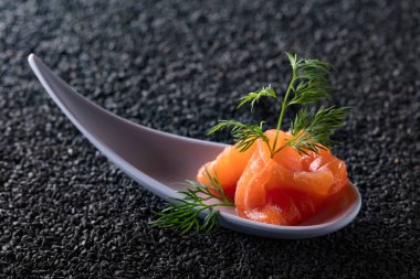 Siyah susam arka plan üzerine dereotu ile tuzlanmış somon.