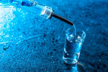 votka ile mavi arka plan ışığı yaktı bir bardak içine dökülür..