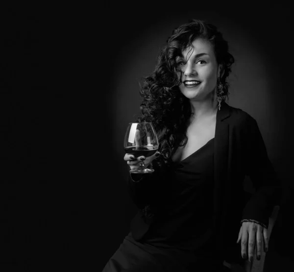 Portret atrakcyjny brunetka z kieliszek brandy na czarnym — Zdjęcie stockowe