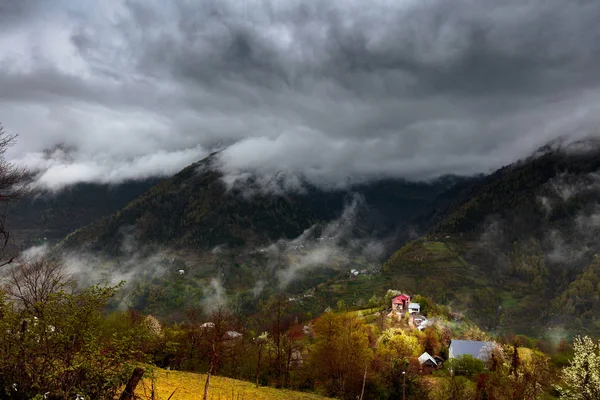 Caucasus village and mountains on dark moody day with big clouds — Stock Photo, Image