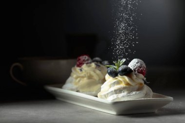 Tatlı Pavlova ile pudra şekeri serpilir.