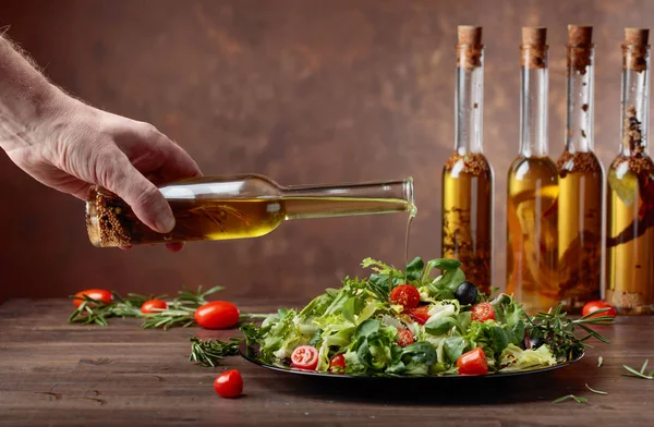 Зеленый салат с оливковым маслом, выливающимся из маленькой бутылки . — стоковое фото
