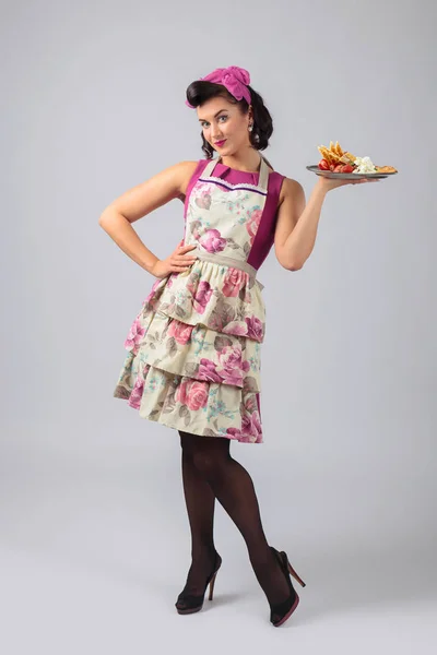 Piękna młoda gospodyni w fioletowej sukni i fartuch z deserem — Zdjęcie stockowe