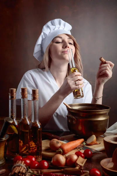 Mladá žena v kuchařní uniformě s malými lahvemi rostlinného oleje — Stock fotografie
