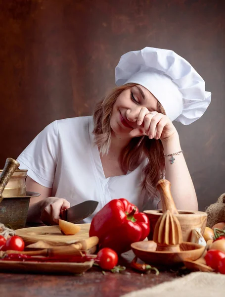 Mladá žena v kuchařské uniformě krájí cibuli a pláče. — Stock fotografie