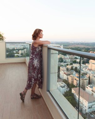 Balkondaki kadın akşam şehrine bakıyor..