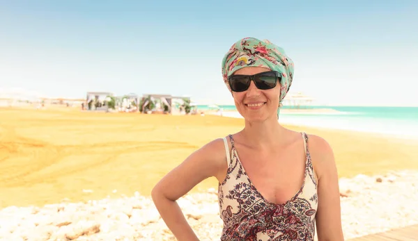 Happy woman in sunglasses on a beach of dead sea. — Stock Photo, Image