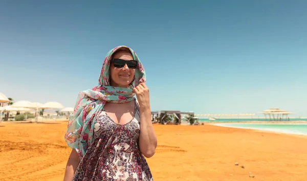 Ευτυχισμένη γυναίκα με γυαλιά ηλίου σε μια παραλία της νεκρής θάλασσας. — Φωτογραφία Αρχείου