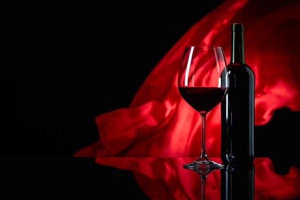 एक काले प्रतिबिंबित पृष्ठभूमि पर वाइनग्लास और लाल शराब की बोतल — स्टॉक फ़ोटो, इमेज