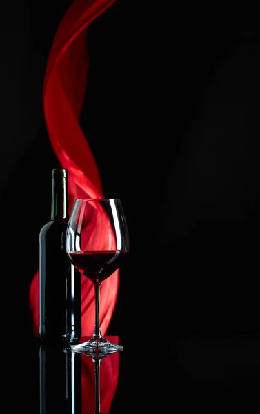 Şarap kadehi ve siyah yansıtıcı backgroun kırmızı şarap şişesi — Stok fotoğraf