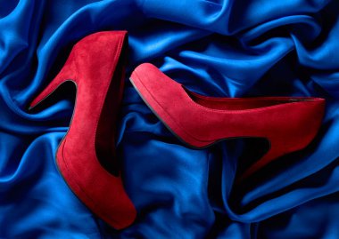 Mavi ipek arka plan üzerinde kırmızı kadın kadife ayakkabı.