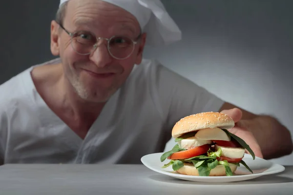 Щасливий шеф-кухар пропонує бутерброд з моцарелою, помідорами та травами — стокове фото