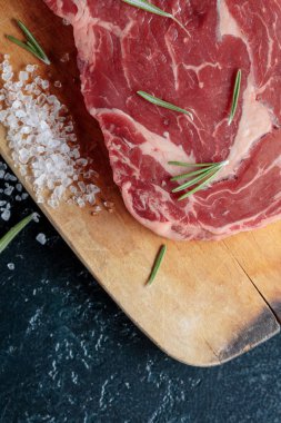  Biberiye ve deniz tuzu ile ahşap tahta üzerinde pişmemiş sığır eti biftek.