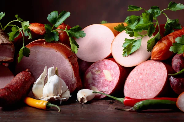 Different sausages, bacon and smoked meats on a  wooden table. — Stock Photo, Image