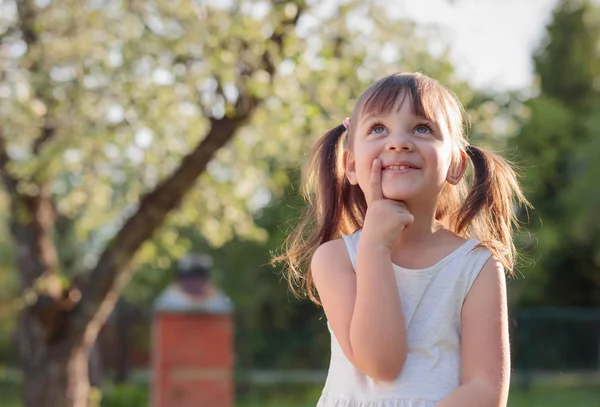 Bonne petite fille rêvant dans le jardin . — Photo