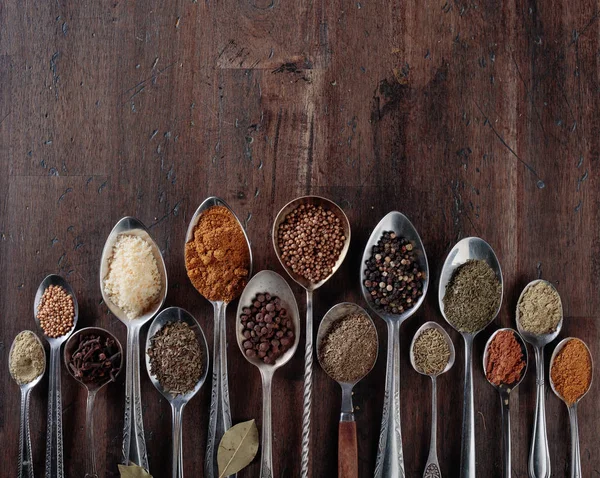 Spezie diverse in cucchiai su uno sfondo di legno . — Foto Stock