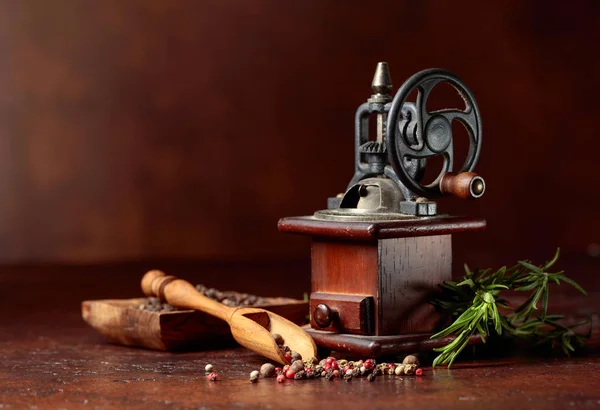 Ancien moulin à poivre avec ustensiles de cuisine, divers poivrons et romarin — Photo