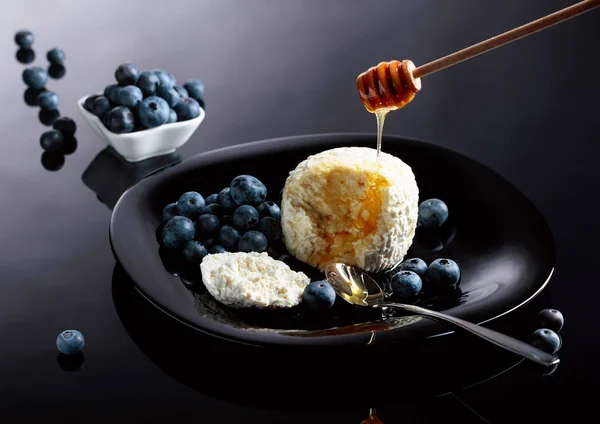 Cottage cheese with honey and blueberry on a black plate. — Stock Photo, Image