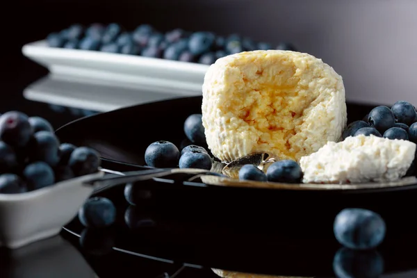 Cottage cheese with honey and blueberry on a black plate. — Stock Photo, Image