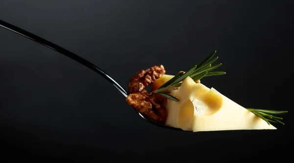 Маасдам сыр с грецкими орехами и розмарином на черном фоне . — стоковое фото
